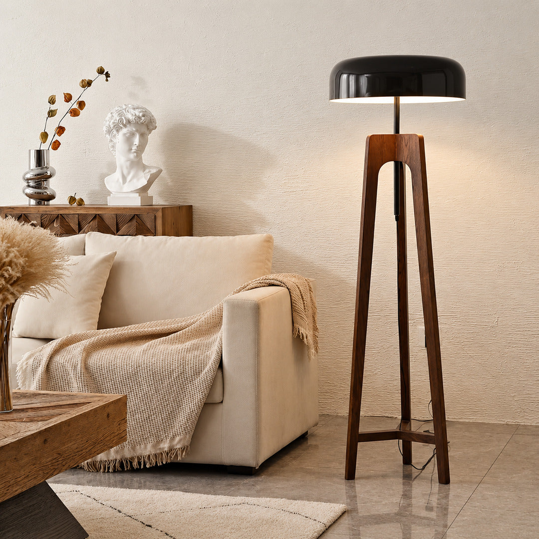 Fungo wood floor lamp standing beside a sofa as a warm sculptural accent in a living room