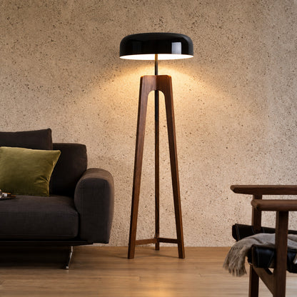 Fungo wood floor lamp standing beside a sofa as a warm sculptural accent in a living room