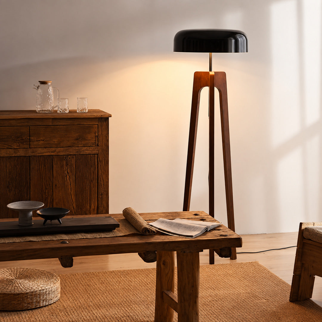 Fungo wood tripod floor lamp filling a living room corner with a soft warm glow