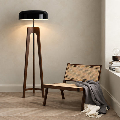 Fungo wood tripod floor lamp filling a living room corner with a soft warm glow