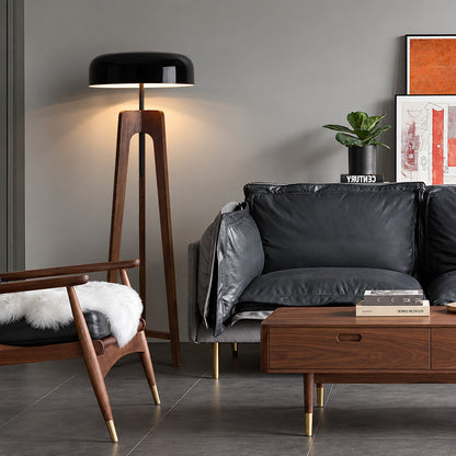 Fungo wood floor lamp standing beside a sofa as a warm sculptural accent in a living room