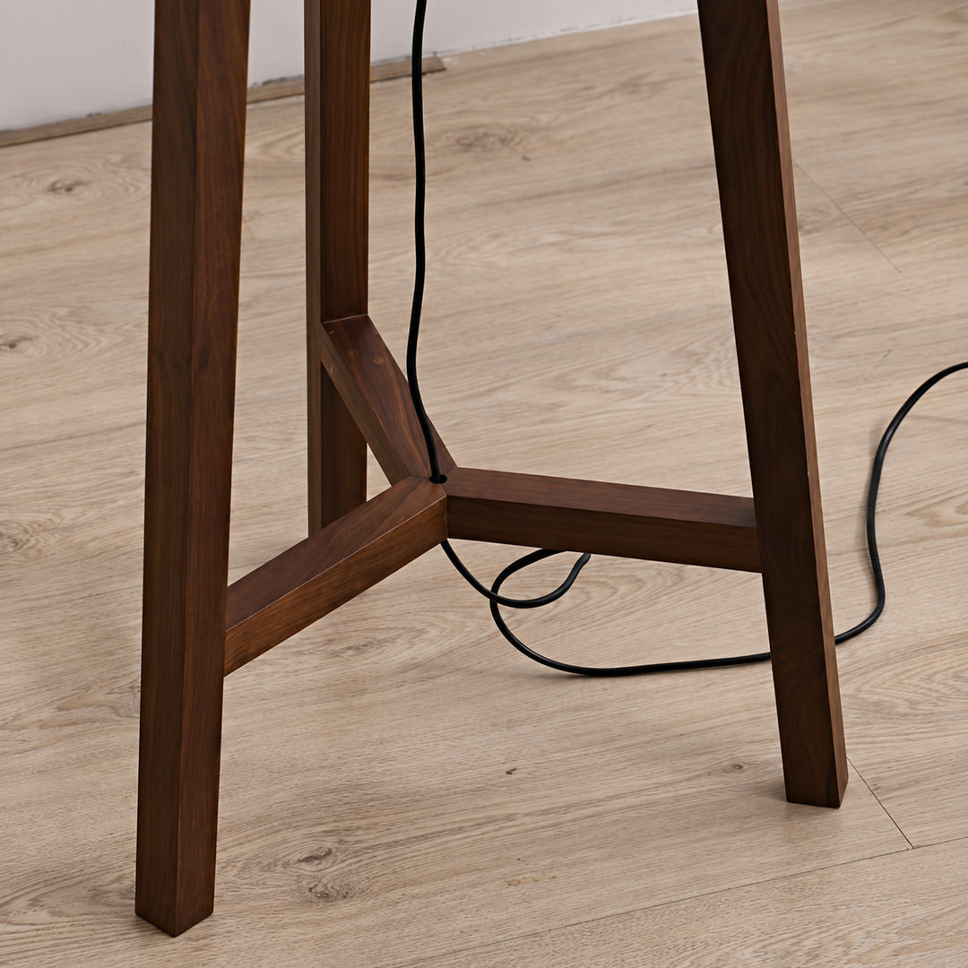 Close-up of the handmade wood tripod base of the Fungo floor lamp showing its rich grain