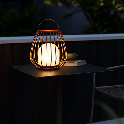 Gabbia rechargeable lantern glowing warmly on a patio dining table at dusk