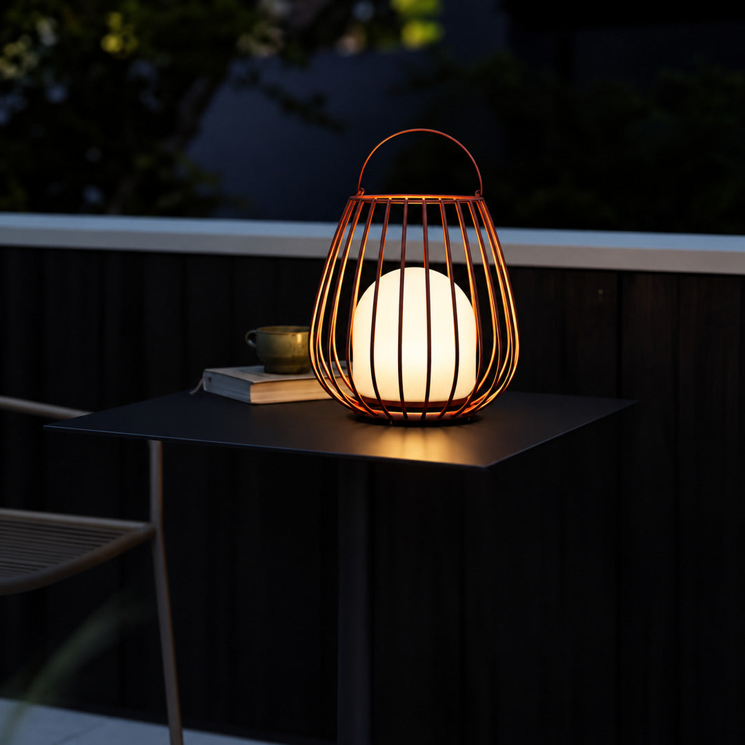 Gabbia rechargeable lantern glowing warmly on a patio dining table at dusk