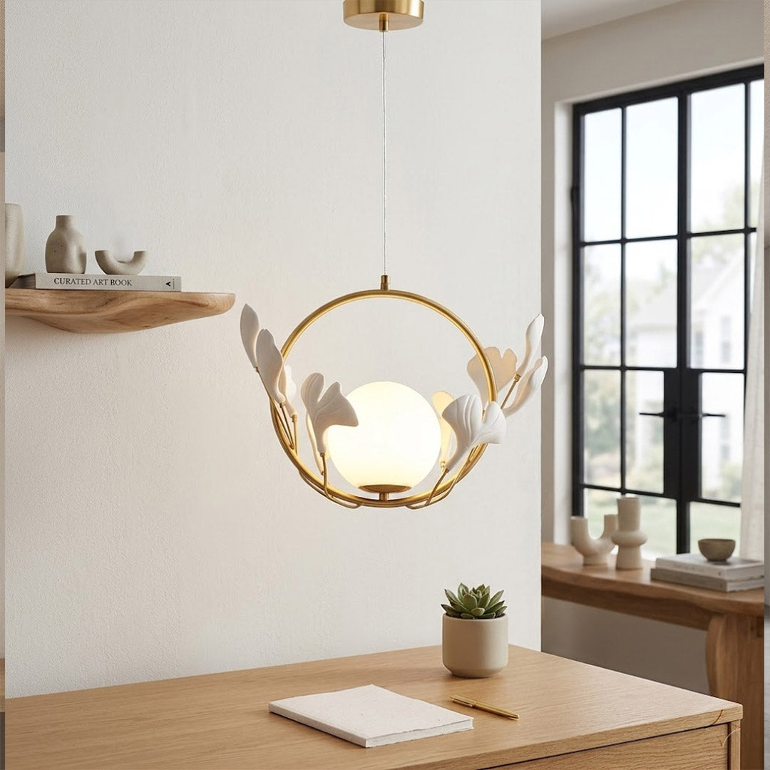 Ginkgo botanical pendant hanging above oval dining table Japandi interior warm glow porcelain leaves brass halo