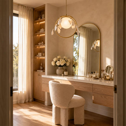 Ginkgo leaf brass porcelain pendant light illuminating an elegant oak vanity table with an arched mirror.