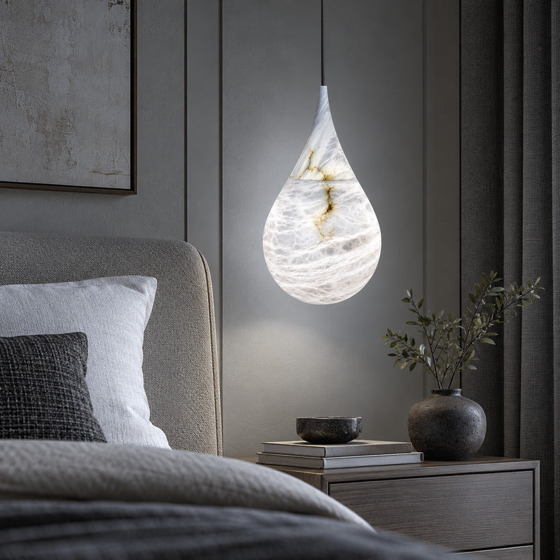 Single Goccia alabaster raindrop pendant hanging beside a modern bedroom nightstand