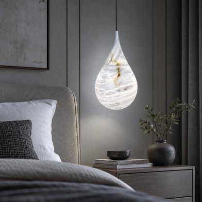 Single Goccia alabaster raindrop pendant hanging beside a modern bedroom nightstand