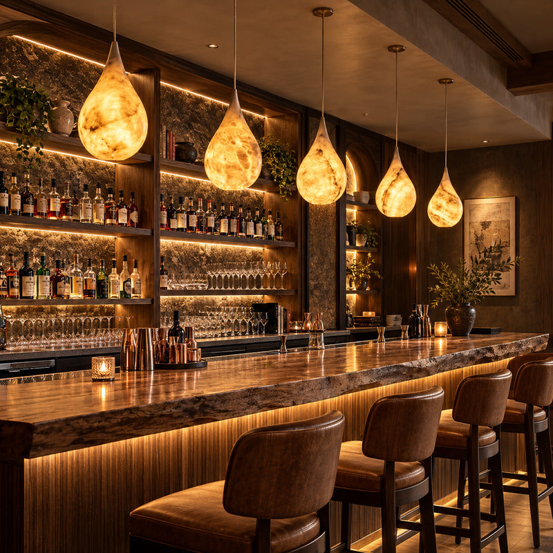 Cluster of Goccia alabaster raindrop pendants over a cocktail bar counter with a warm glow