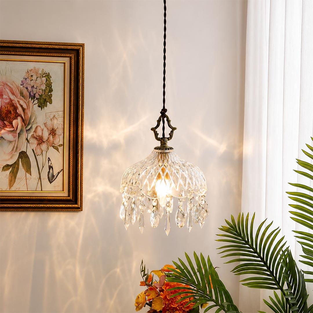 Close-up detail of Goldie vintage brass pendant light featuring an ornate brass hanger, textured cut glass bowl shade, and sparkling hanging crystal droplets with a glowing warm bulb.