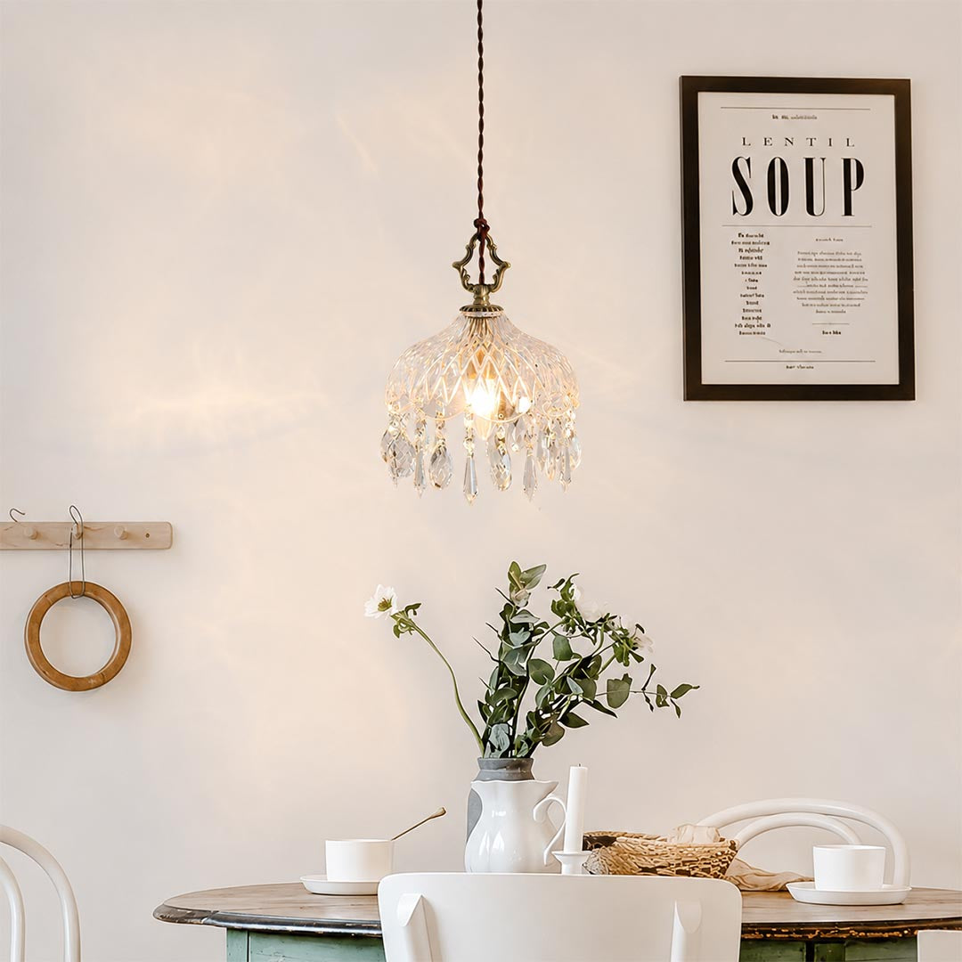 Close-up detail of Goldie vintage brass pendant light featuring an ornate brass hanger, textured cut glass bowl shade, and sparkling hanging crystal droplets with a glowing warm bulb.