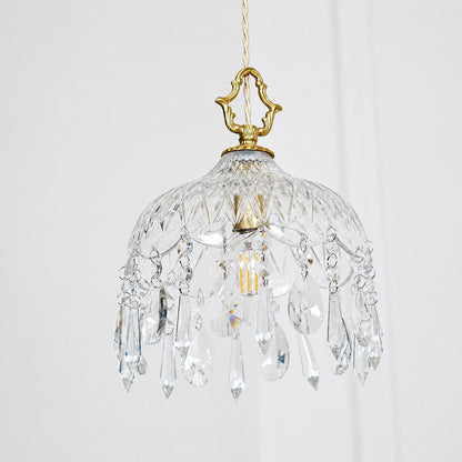 Close-up detail of Goldie vintage brass pendant light featuring an ornate brass hanger, textured cut glass bowl shade, and sparkling hanging crystal droplets with a glowing warm bulb.