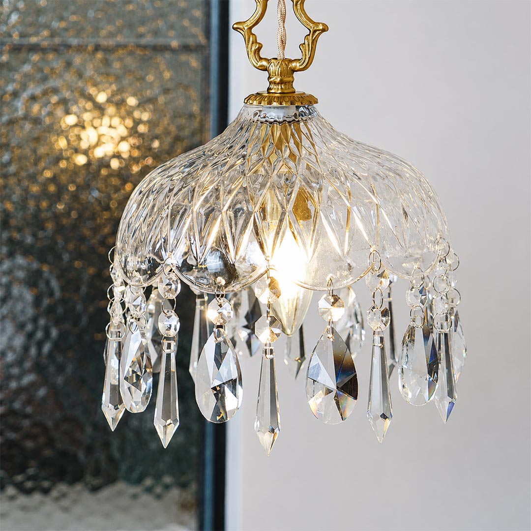 Close-up detail of Goldie vintage brass pendant light featuring an ornate brass hanger, textured cut glass bowl shade, and sparkling hanging crystal droplets with a glowing warm bulb.