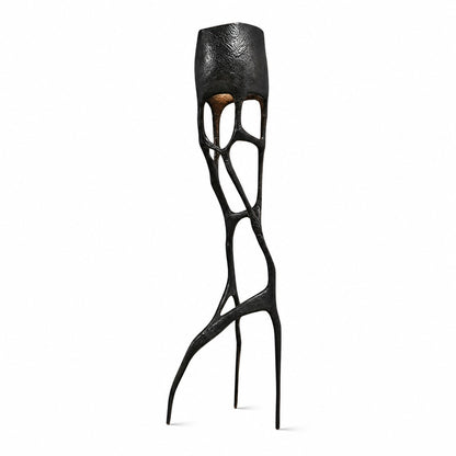 Gotica sculpture floor lamp with an intricate gothic web-like base glowing warm in a modern living room