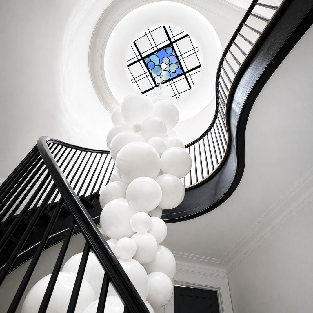 Grappolo glass chandelier flowing down an open staircase stairwell like a cluster of globes