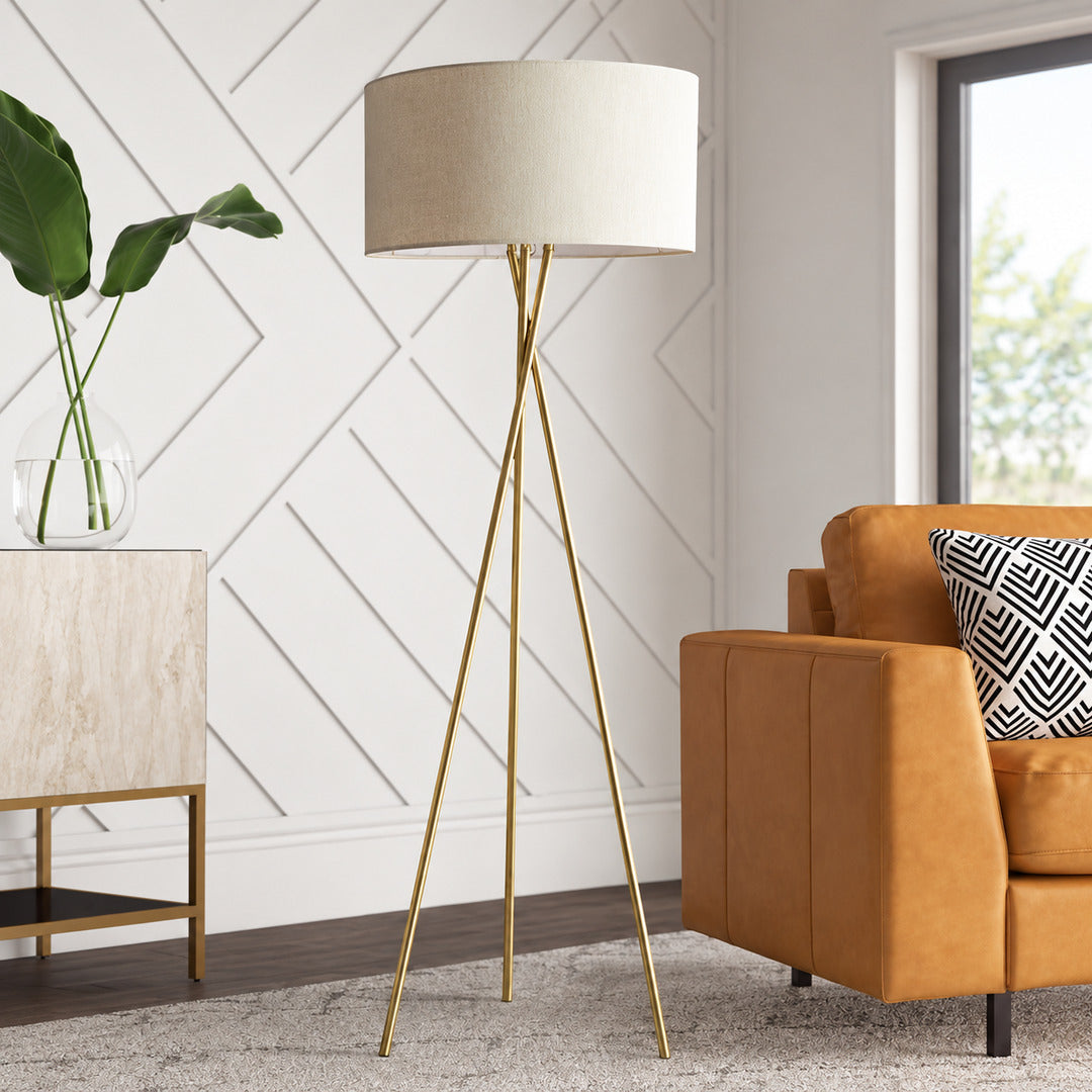 Grazia floor lamp standing beside a sofa as a minimalist gold accent in a living room