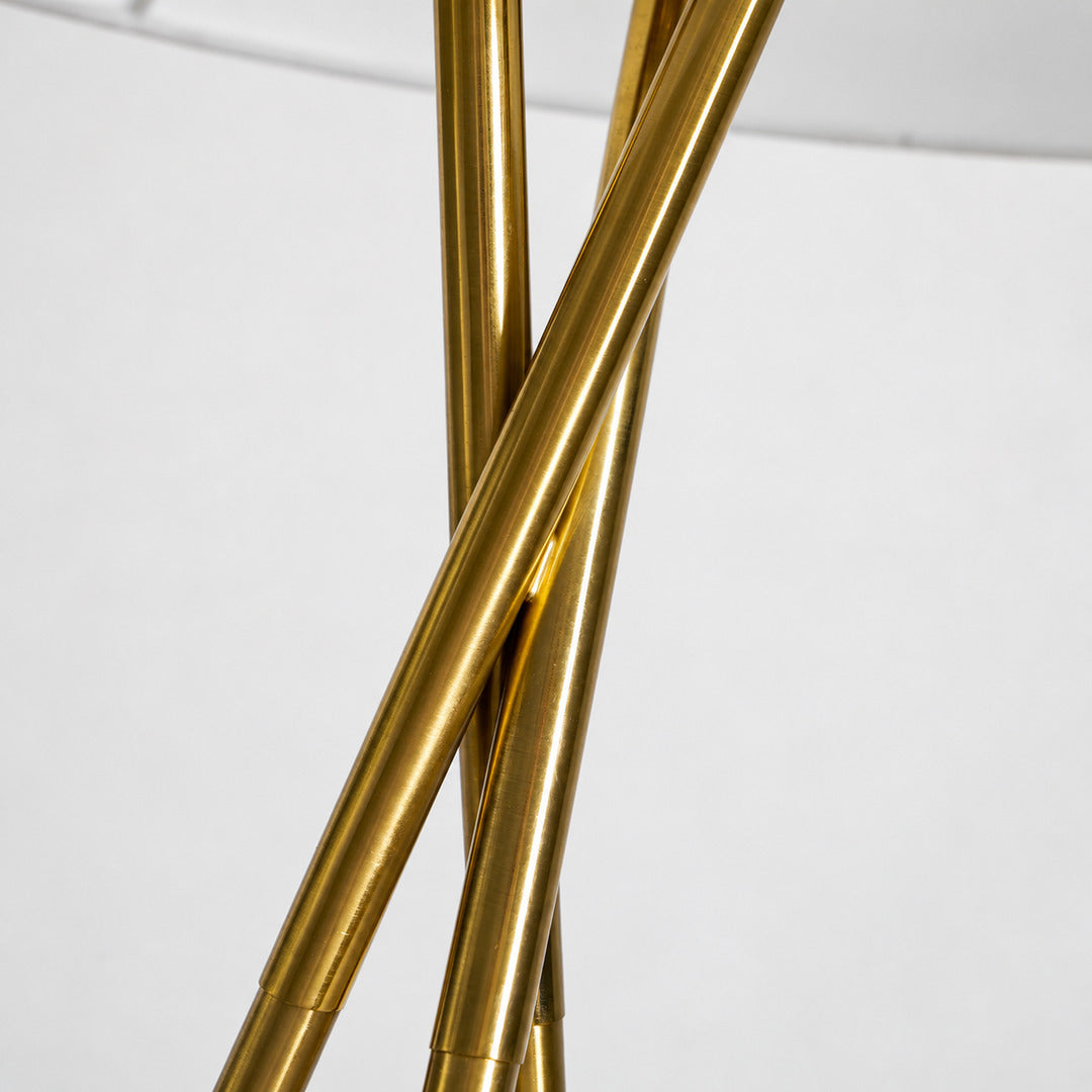 Close-up of the slim gold metal tripod base of the Grazia floor lamp