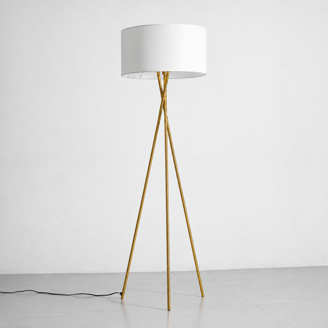Grazia gold tripod floor lamp with a white fabric shade standing beside a modern sofa
