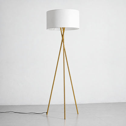 Grazia gold tripod floor lamp with a white fabric shade standing beside a modern sofa