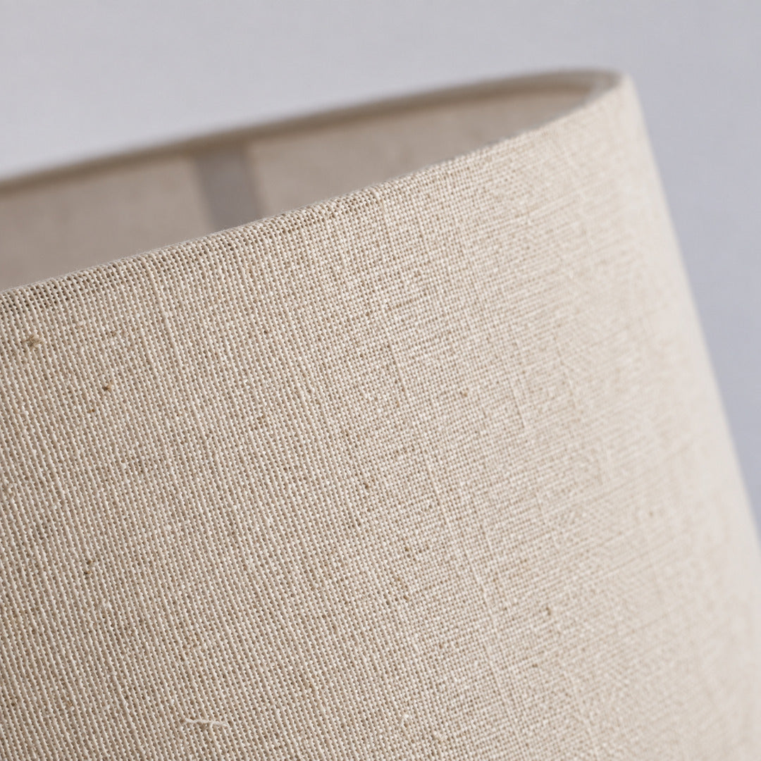 Detail of the soft fabric drum shade in white or linen diffusing a warm glow on the Grazia floor lamp