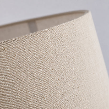 Detail of the soft fabric drum shade in white or linen diffusing a warm glow on the Grazia floor lamp