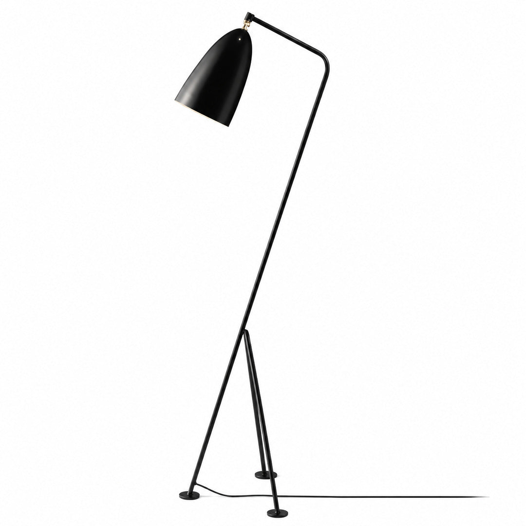 Grillo floor lamp with a slim angled metal body and adjustable conical shade glowing warm in a reading corner