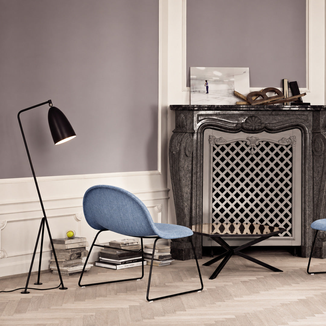 Grillo floor lamp angled over an armchair to provide focused warm reading light