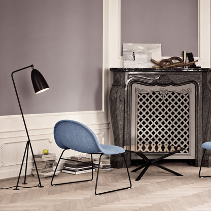 Grillo floor lamp angled over an armchair to provide focused warm reading light