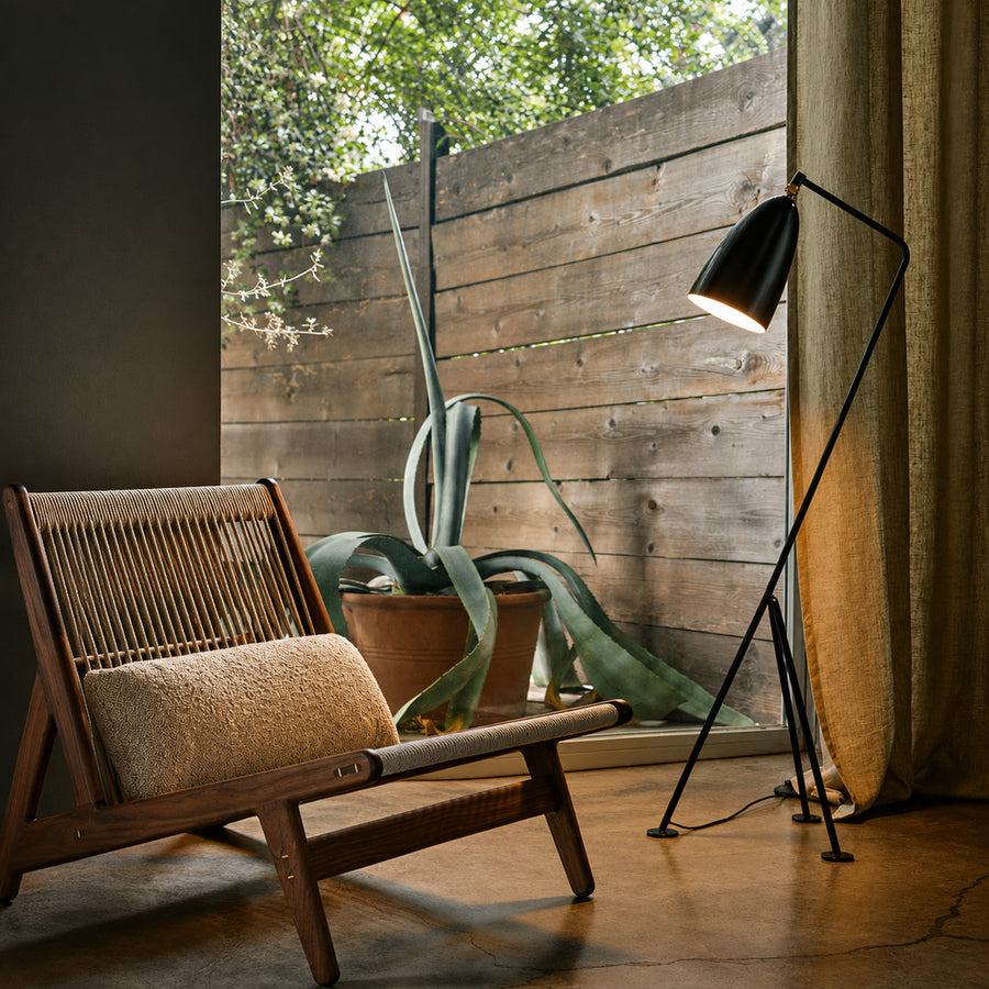 Grillo floor lamp angled over an armchair to provide focused warm reading light