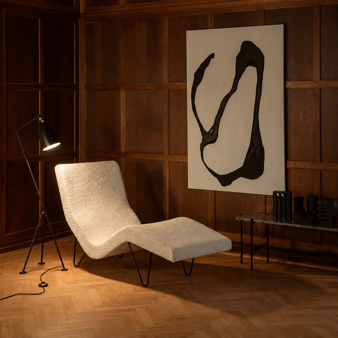 Grillo floor lamp angled over an armchair to provide focused warm reading light