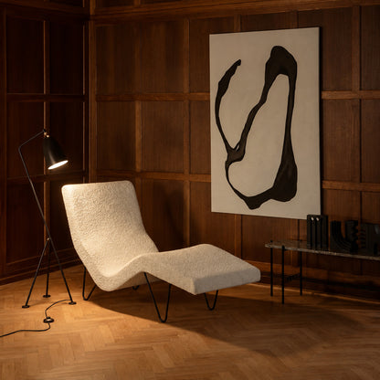 Grillo floor lamp angled over an armchair to provide focused warm reading light