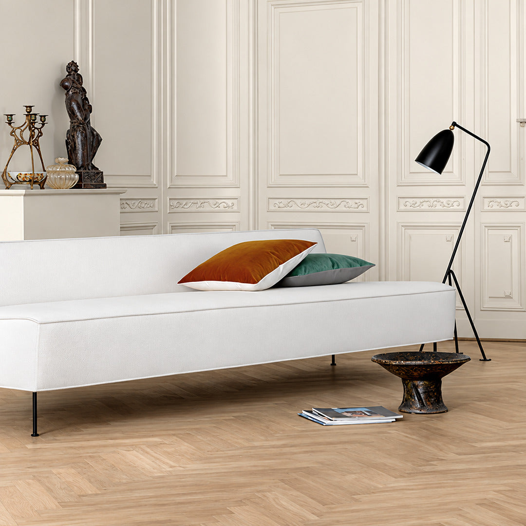 Grillo floor lamp standing beside a sofa directing task light in a modern living room