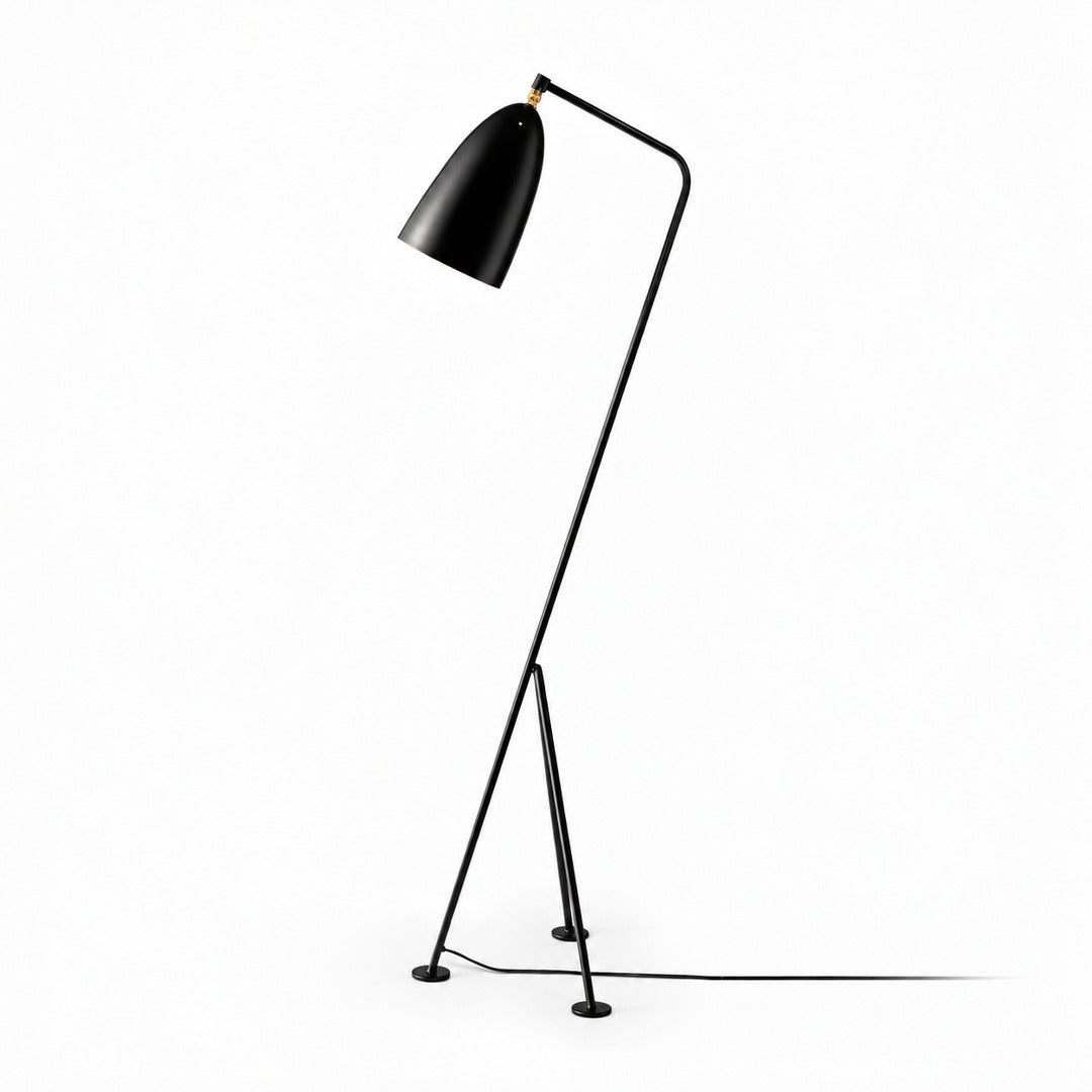 Black Grillo angled metal floor lamp providing warm task light beside a reading chair
