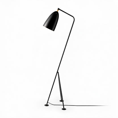 Black Grillo angled metal floor lamp providing warm task light beside a reading chair