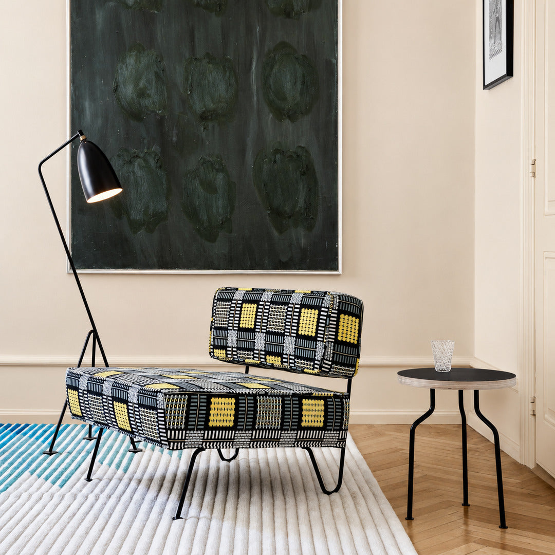 Grillo floor lamp angled over an armchair to provide focused warm reading light