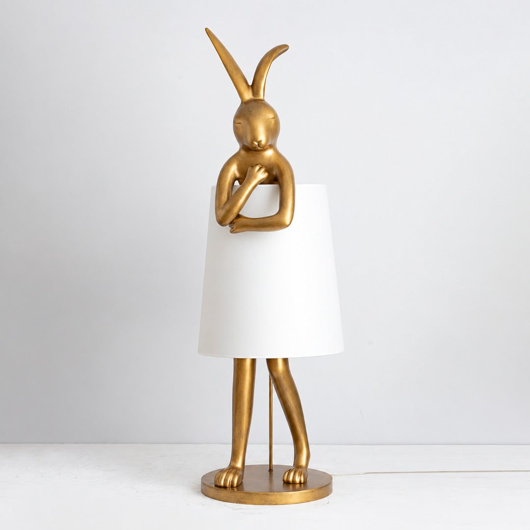 Vintage gold Hare silhouette table lamp with a white shade on a living room console
