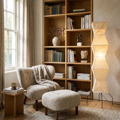 Sunlit Japandi room corner showcasing a glowing Akari UF4-L9 Floor Lamp near a plush lounge chair by Stuber Lighting.