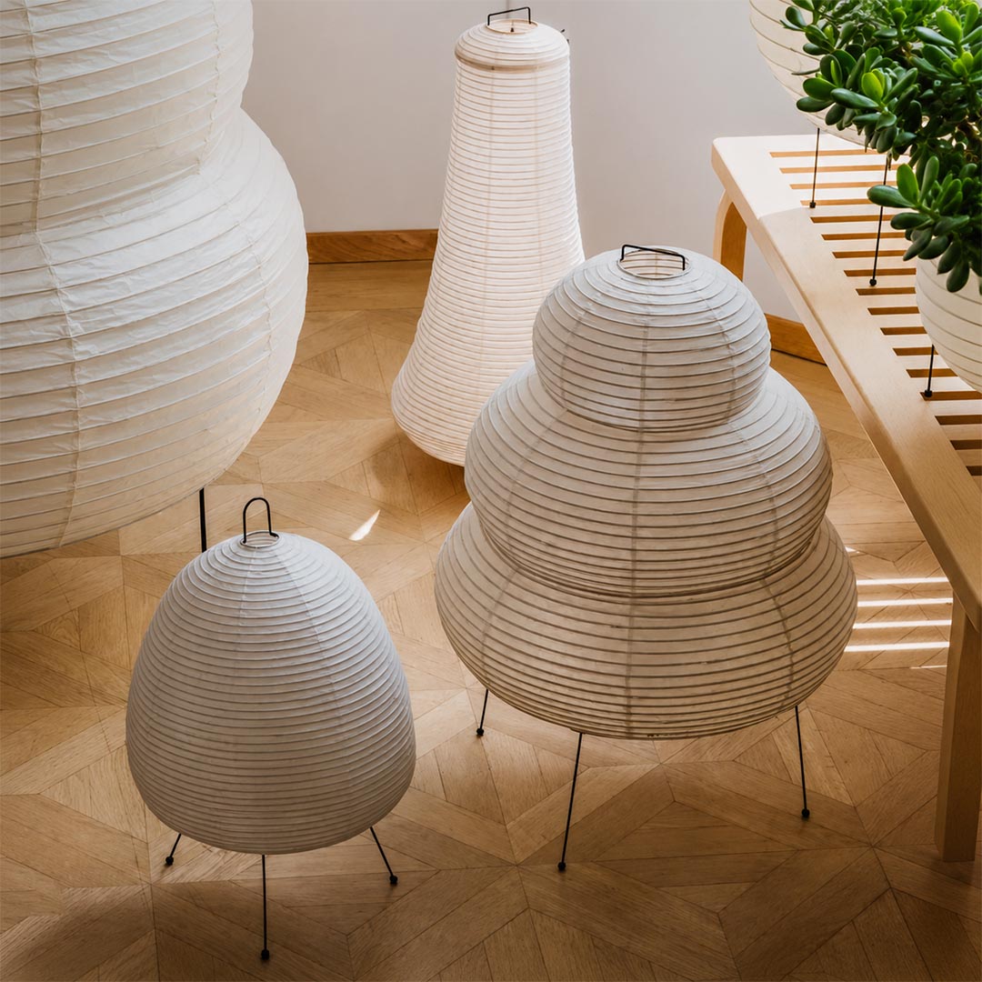 A curated collection of mid-century Japanese style Washi paper lantern lamps displayed on a wooden platform by Stuber Lighting.