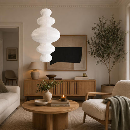 Organic modern multi-tier paper lantern chandelier by Stuber Lighting centered above a contemporary living room coffee table and cream sofa
