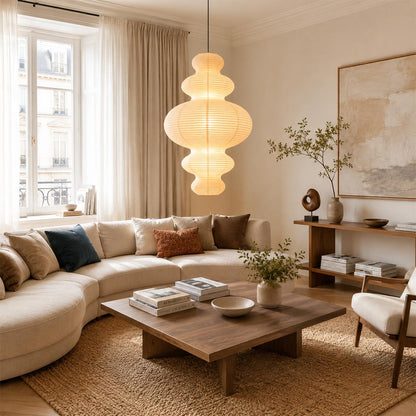 Organic modern multi-tier paper lantern chandelier by Stuber Lighting centered above a contemporary living room coffee table and cream sofa.
