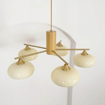 Juno brass chandelier above dining table warm glow glass shades elegant interior