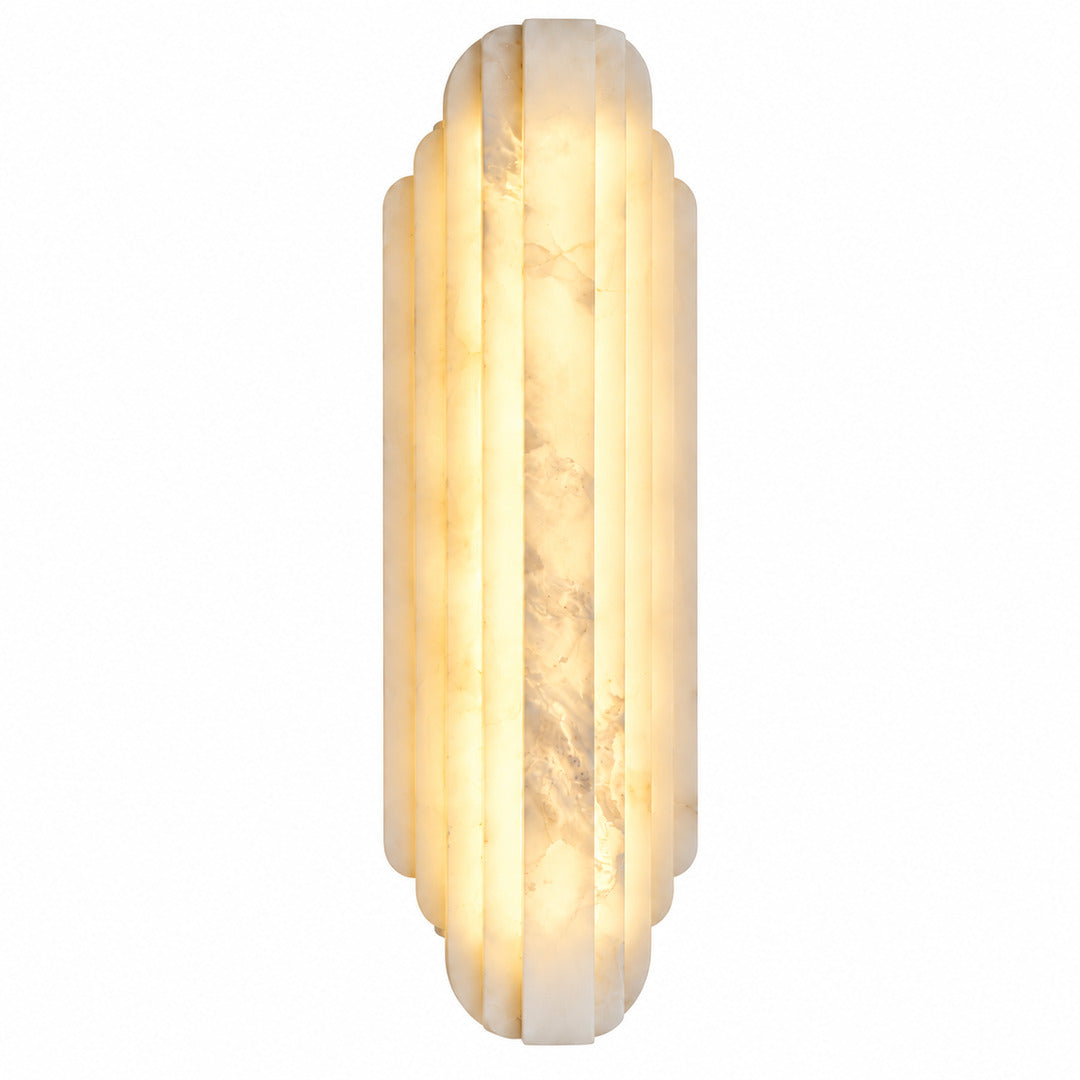 Lamina alabaster wall sconce glowing warm beside a bed in a modern bedroom