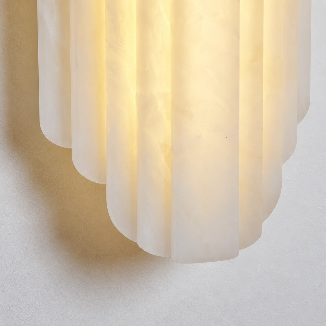Close-up of natural veining glowing through the layered alabaster discs of the Lamina wall sconce