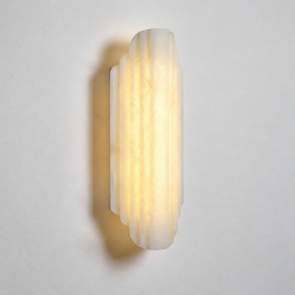 Lamina wall sconce with stacked natural alabaster discs on a slim metal base on a white background