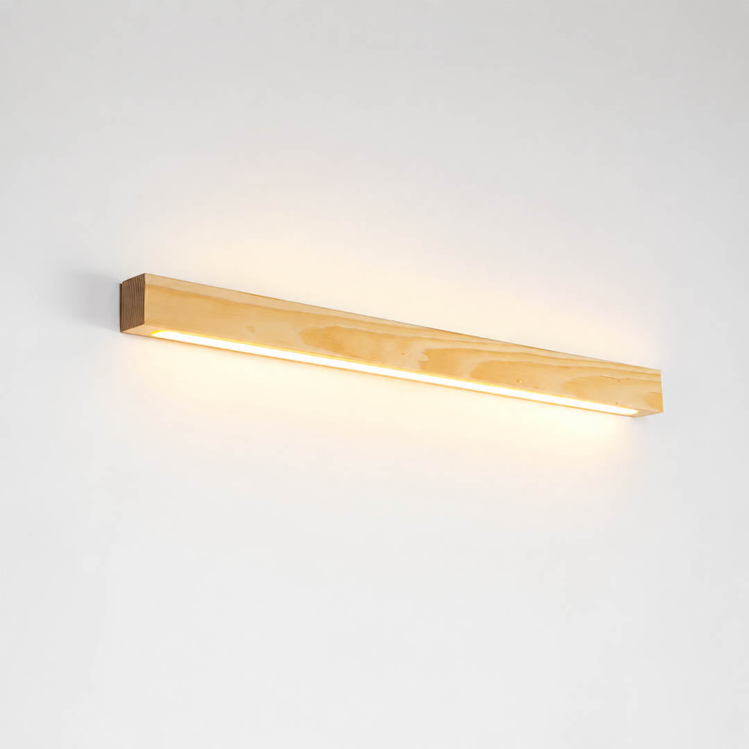 Larsson linear wood wall light natural pine wood color integrated LED warm glow slim bar white background front view
