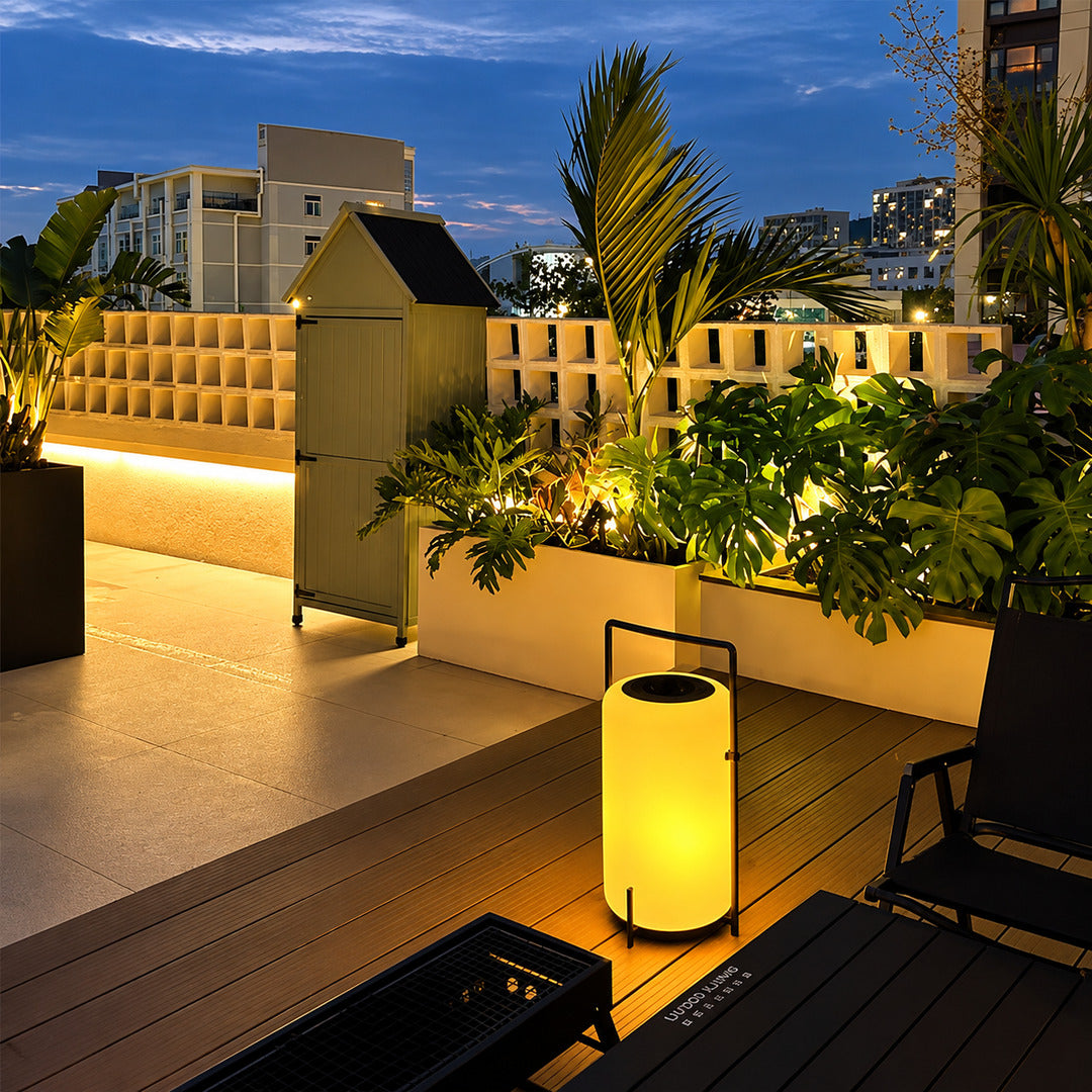 Tall Lucciola rechargeable floor lantern standing on a deck beside outdoor seating