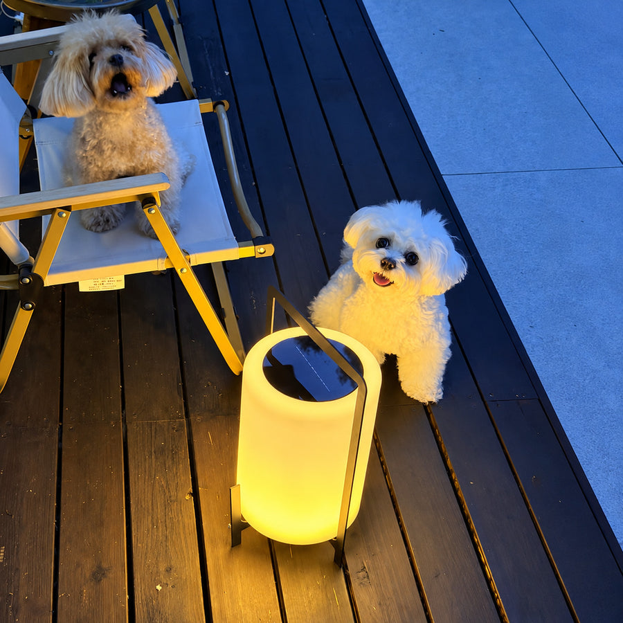 Tall Lucciola rechargeable floor lantern standing on a deck beside outdoor seating
