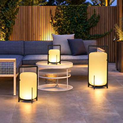 Lucciola rechargeable lantern glowing warmly on a patio dining table at dusk