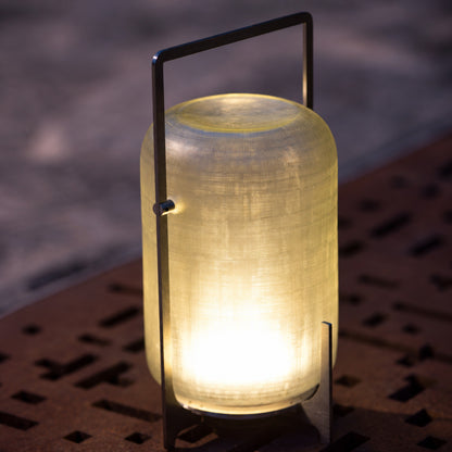 Warm evening glow of the Lucciola rechargeable lantern creating a cozy outdoor mood after dark