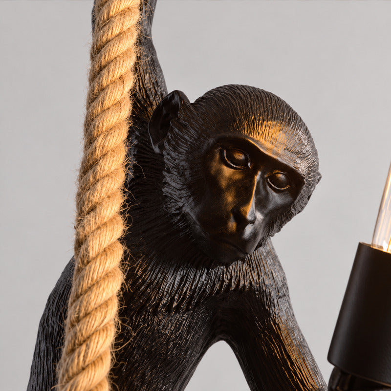 Close-up of the detailed resin monkey sculpture holding a bulb on the Monkey pendant light